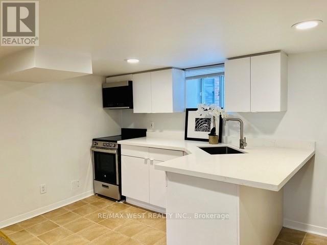 A white kitchen with a black fridge and a black microwave.
