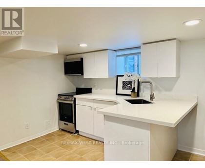 A white kitchen with a black fridge and a black microwave.