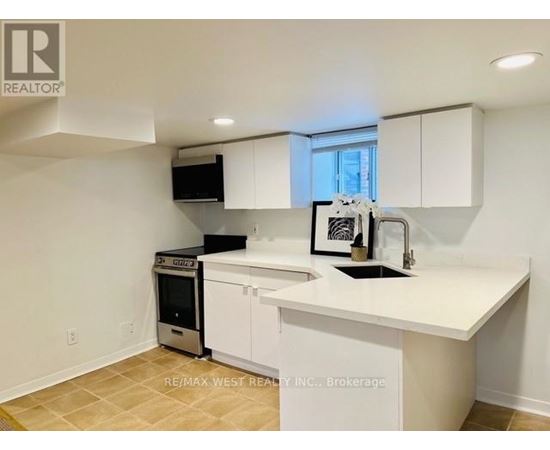 A white kitchen with a black fridge and a black microwave.