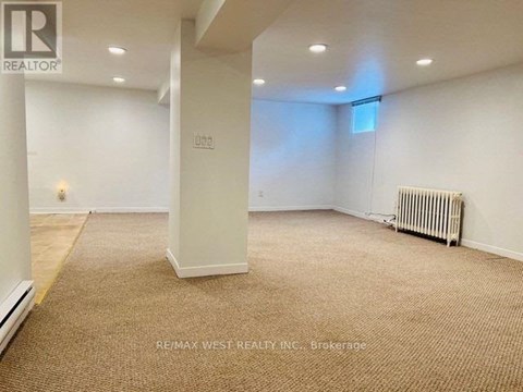 A spacious room with a carpeted floor and a radiator on the wall.