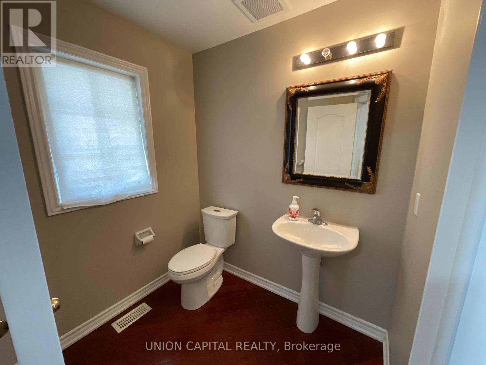 A bathroom with a toilet, sink, and mirror.