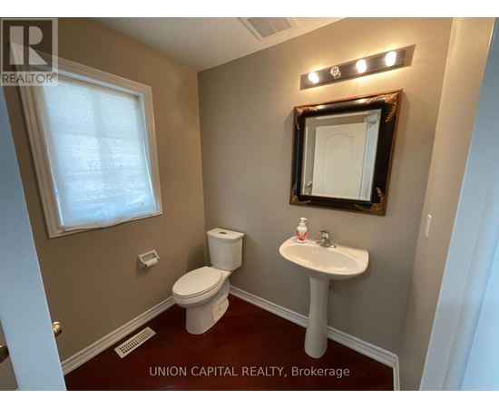 A bathroom with a toilet, sink, and mirror.