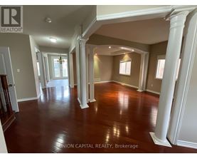 A spacious room with wooden floors and white columns.