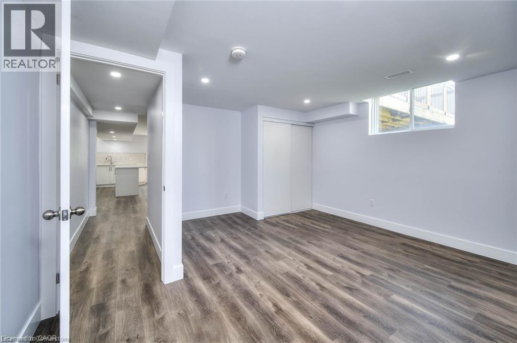 A spacious room with wood flooring and white walls.
