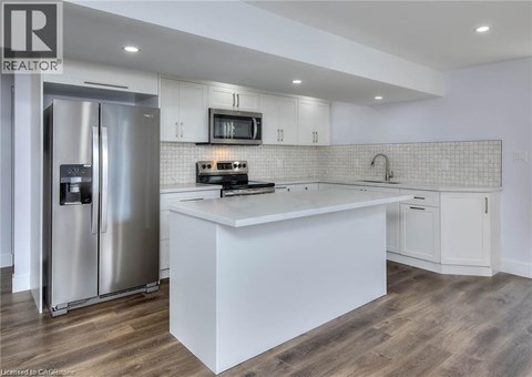 A modern kitchen with a stainless steel refrigerator and white countertops.