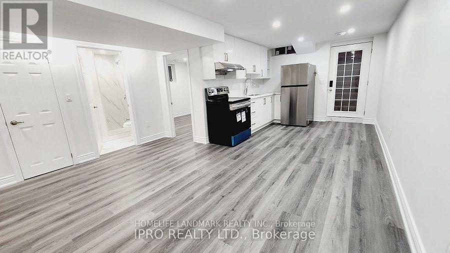 A kitchen area with a refrigerator, oven, and cabinets.