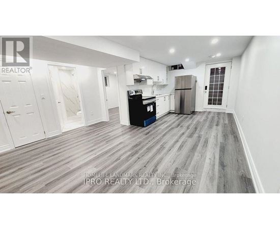 A kitchen area with a refrigerator, oven, and cabinets.