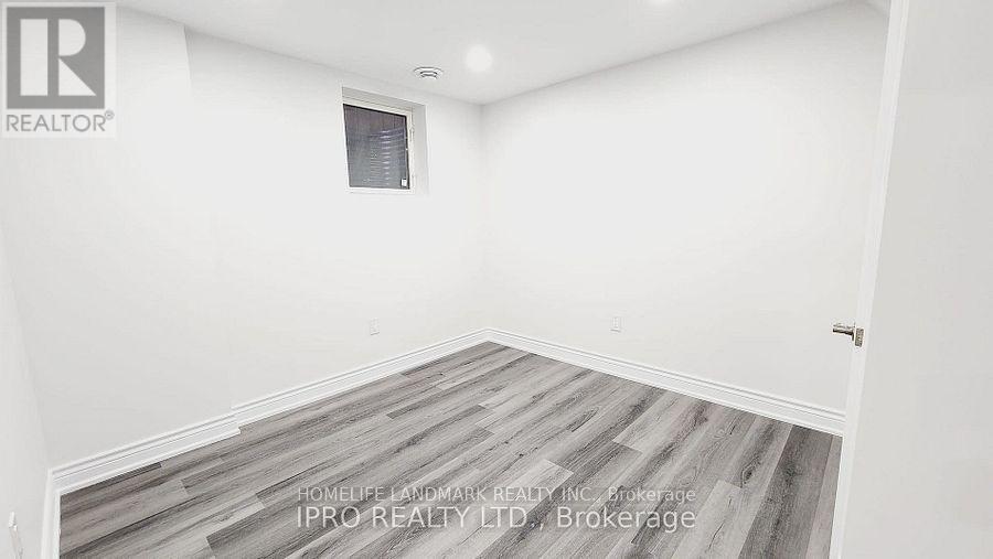 A room with a wooden floor and white walls, with a window and a door.