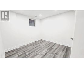 A room with a wooden floor and white walls, with a window and a door.