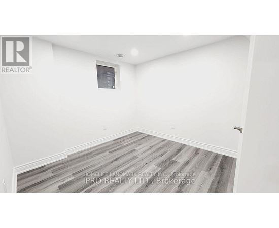 A room with a wooden floor and white walls, with a window and a door.