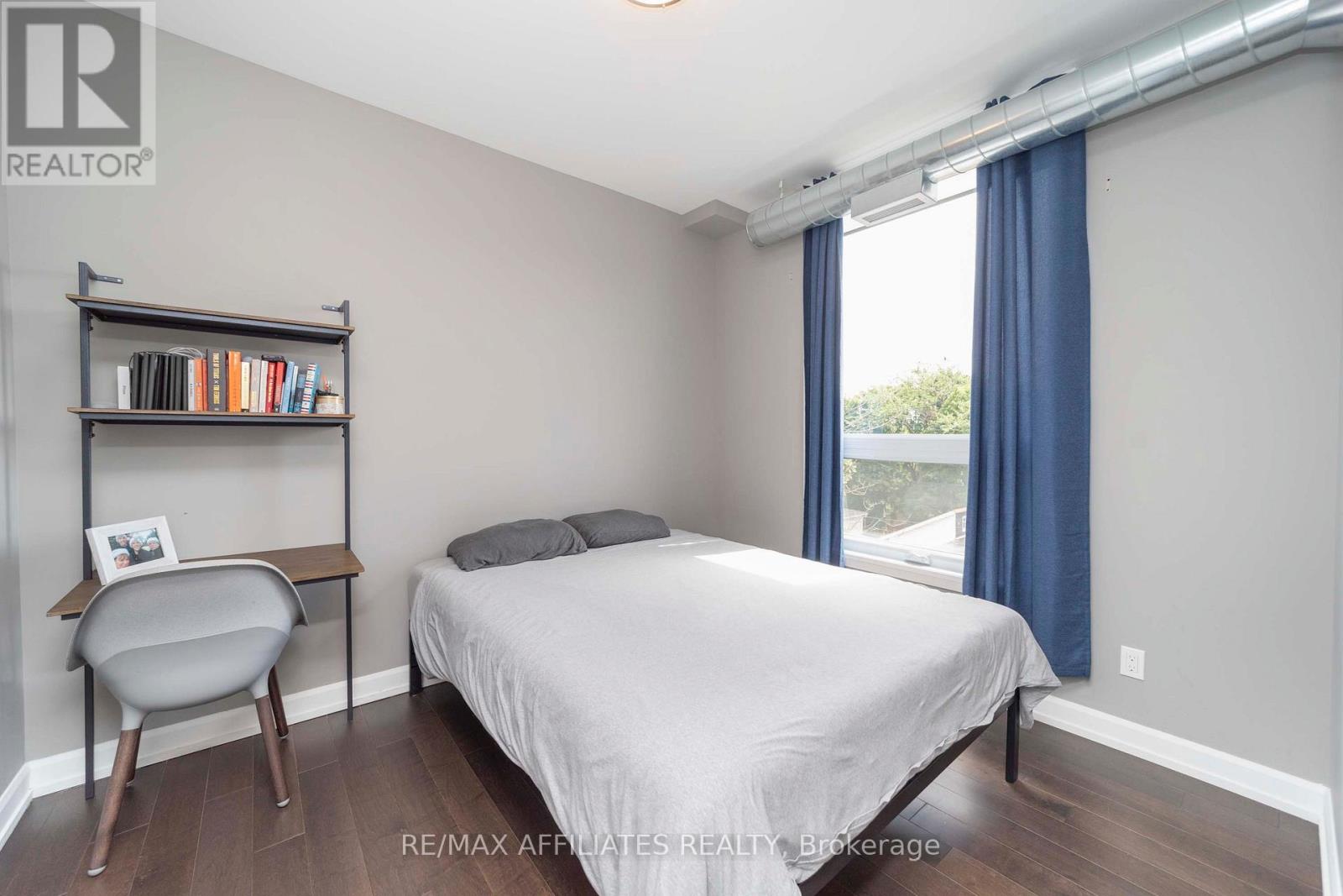 A bedroom with a bed, chair, and bookshelf.