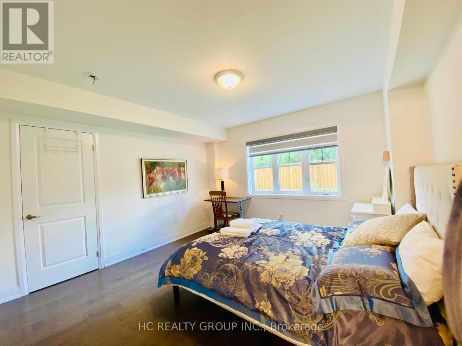 A bedroom with a large bed and a painting on the wall.