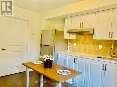 A kitchen with a table and a refrigerator.