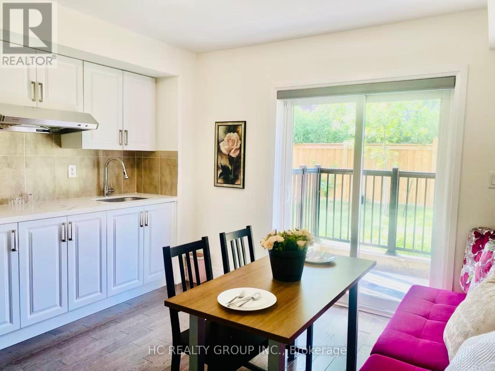 A dining room with a table set for two and a view of a backyard.