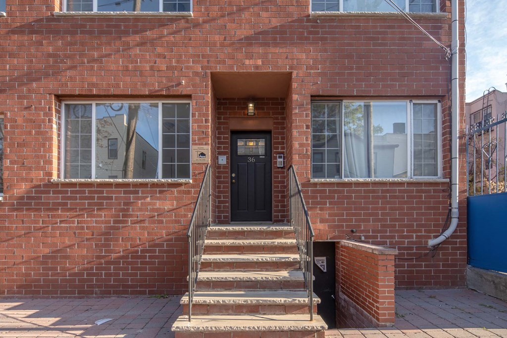 the front of a brick house with stairs and a black door