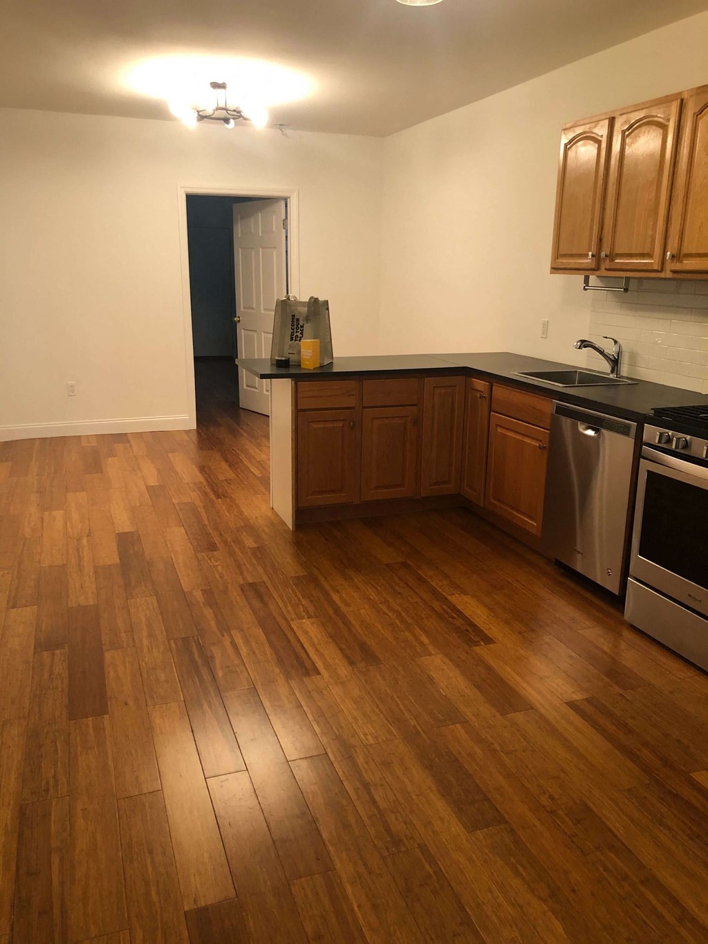 an empty kitchen with wooden floors and stainless steel appliances