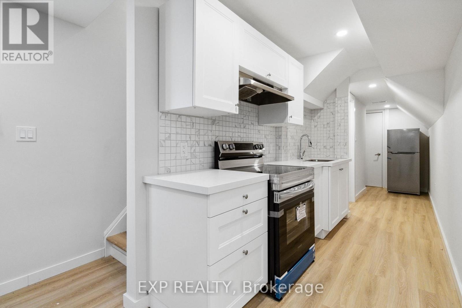 A kitchen with white cabinets and a wooden floor.