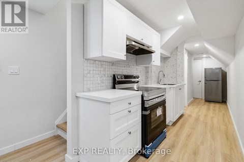 A kitchen with white cabinets and a wooden floor.