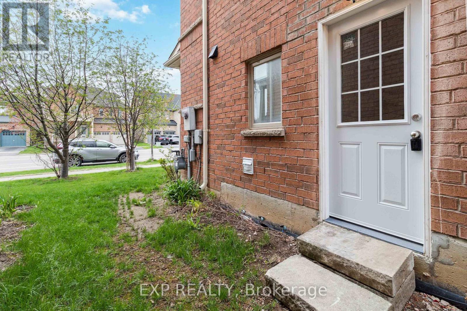 A white door is on the right side of a brick building.