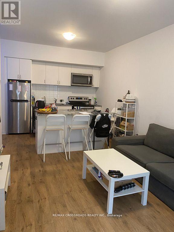 A kitchen with a refrigerator, oven, and microwave.
