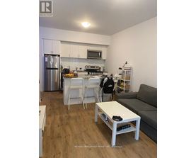 A kitchen with a refrigerator, oven, and microwave.
