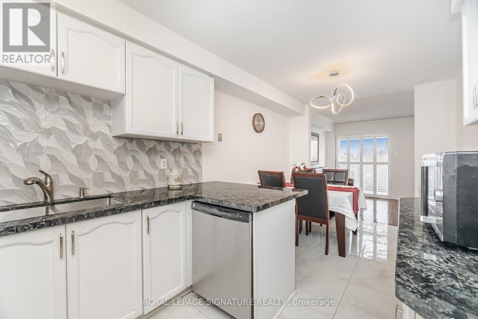 A kitchen with white cabinets and a black countertop.