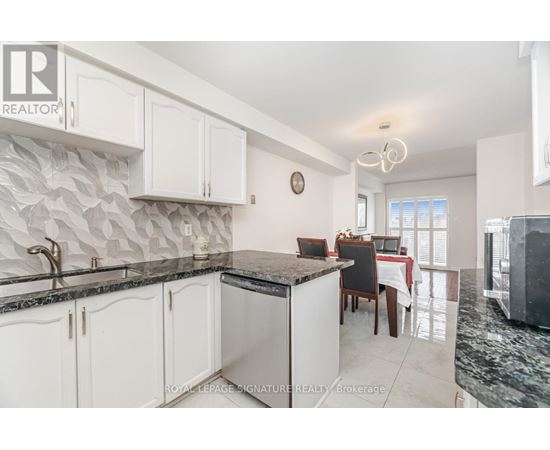 A kitchen with white cabinets and a black countertop.