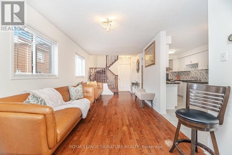 A living room with a brown leather couch and a wooden floor.