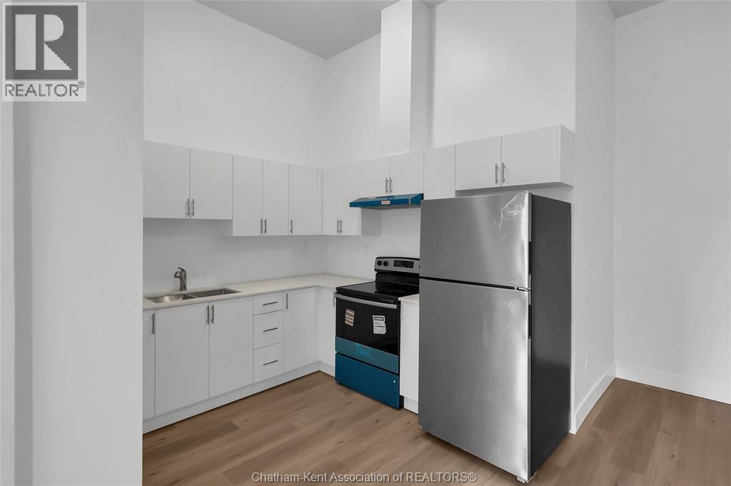 A kitchen with white cabinets and a stainless steel refrigerator.