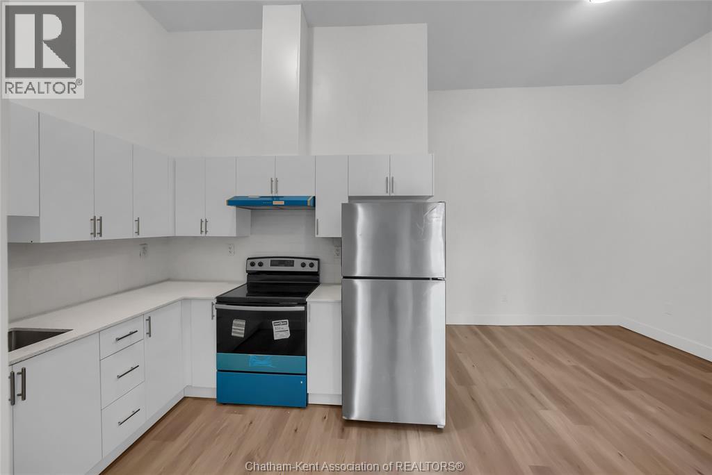 A kitchen with white cabinets and a stainless steel refrigerator.