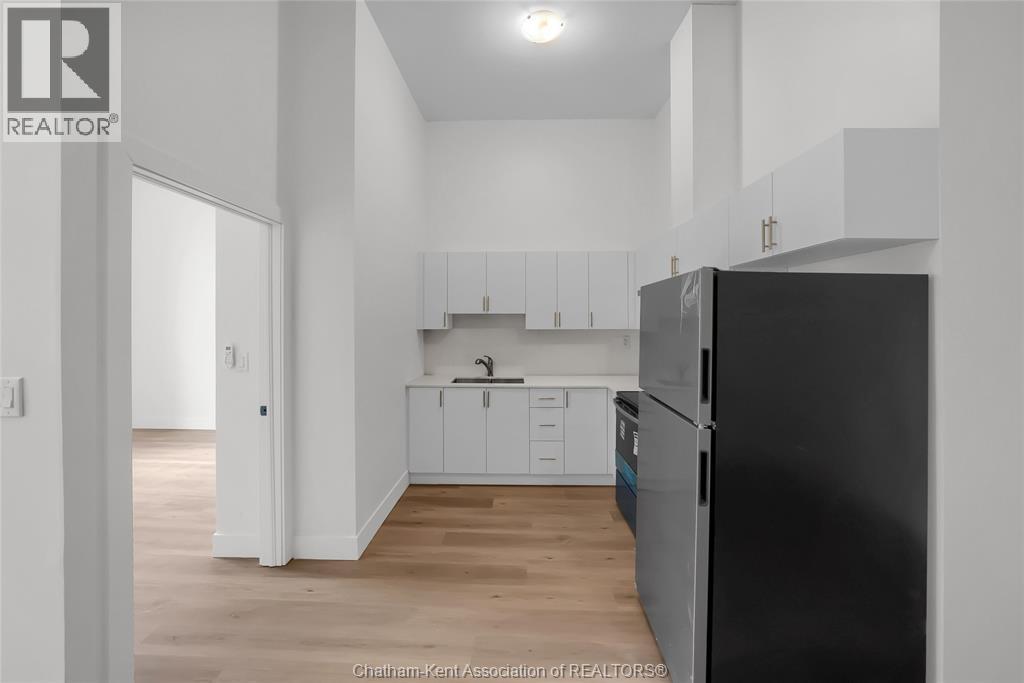A kitchen with white cabinets and a black refrigerator.