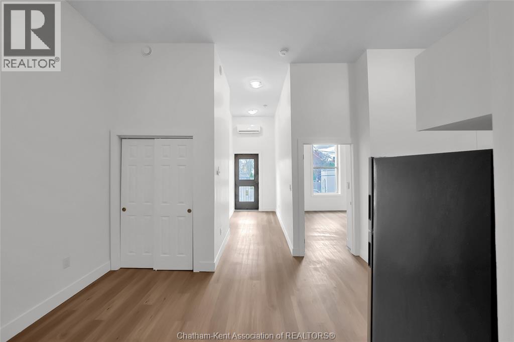 A spacious room with wooden flooring and white walls.