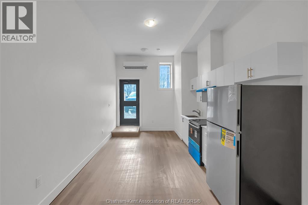A kitchen with a refrigerator and a countertop with a blue container on it.