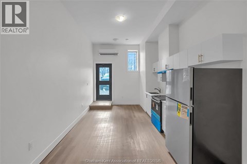 A kitchen with a refrigerator and a countertop with a blue container on it.