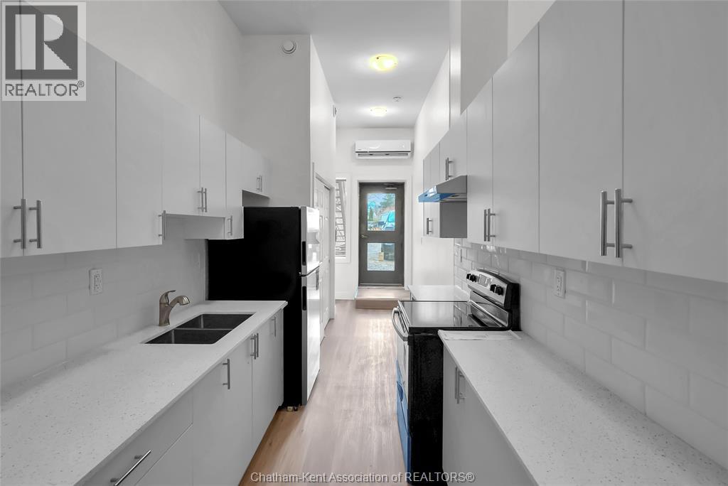 A modern kitchen with white cabinets and a black refrigerator.