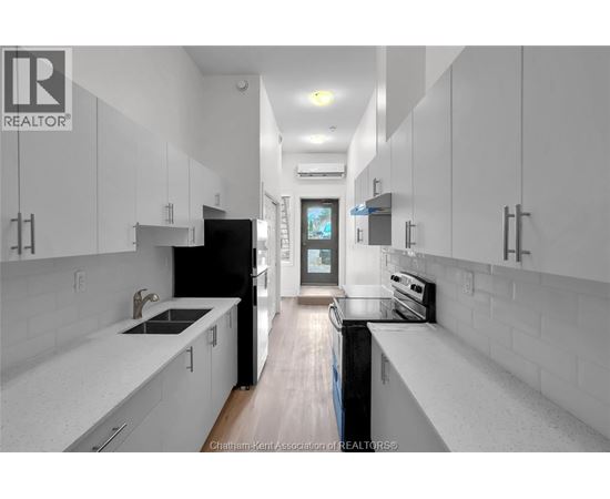 A modern kitchen with white cabinets and a black refrigerator.