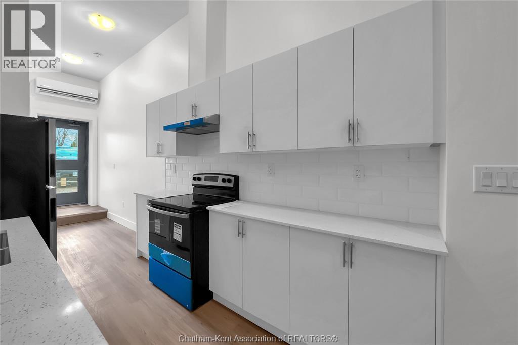 A kitchen with white cabinets and a black fridge.