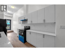 A kitchen with white cabinets and a black fridge.