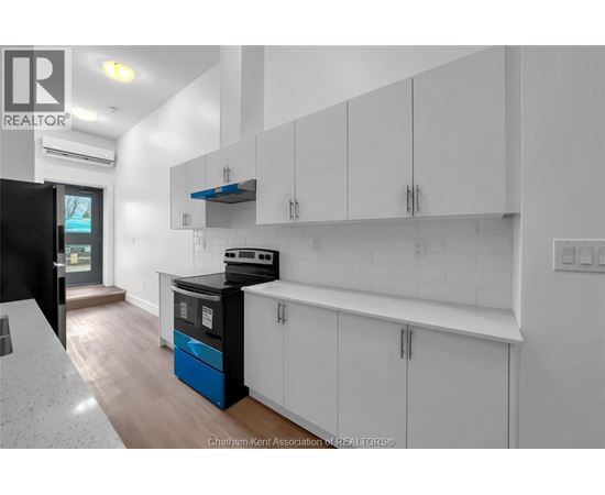 A kitchen with white cabinets and a black fridge.