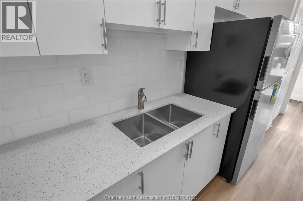 A kitchen with white cabinets and a black refrigerator.