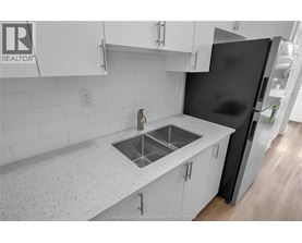 A kitchen with white cabinets and a black refrigerator.