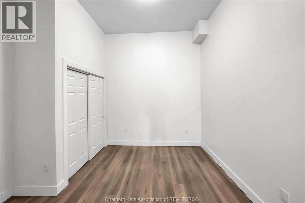 A white room with a wooden floor and a door on the left.