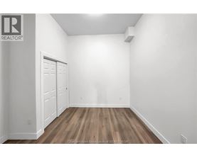A white room with a wooden floor and a door on the left.