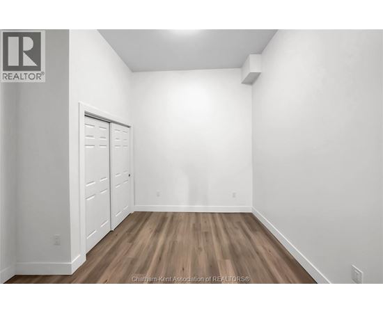 A white room with a wooden floor and a door on the left.