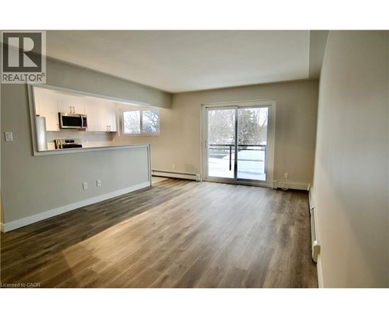 A spacious living room with wood flooring and a large window.