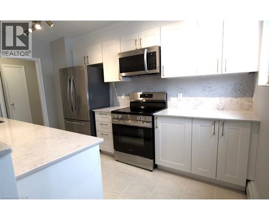 A kitchen with white cabinets and a marble countertop.