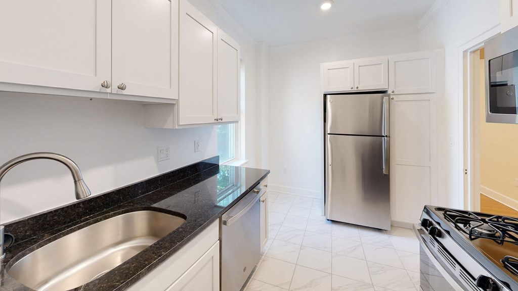 a kitchen with white cabinets and a stainless steel refrigerator