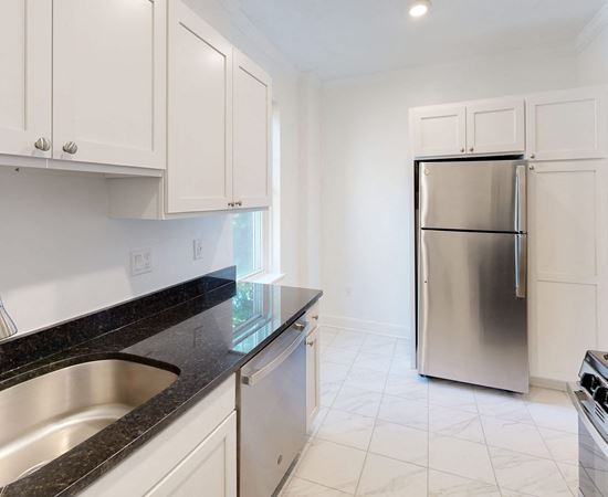 a kitchen with white cabinets and a stainless steel refrigerator