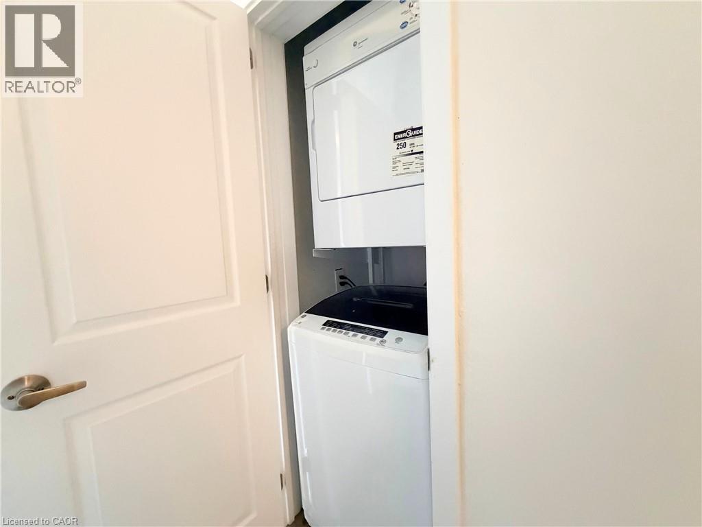 A white washing machine is in a small space between a door and a wall.