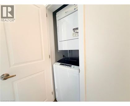 A white washing machine is in a small space between a door and a wall.